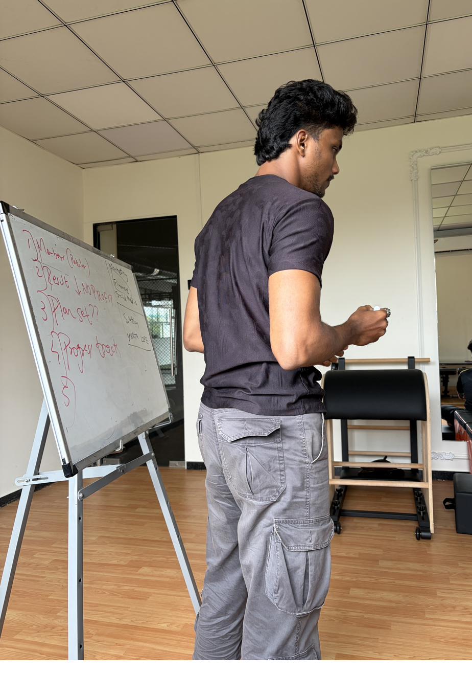 Siddhesh Nagesh Ghatkar coaching a session, writing a client's plan on a whiteboard